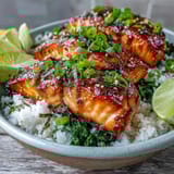 Freshly broiled Miso Glazed Salmon Bowl garnished with green onions, sesame seeds, nori strips, and a lime wedge.