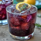 Purple Rain Lavender Lemonade Refresher, a floral and citrusy drink with a stunning purple hue, served over ice.