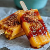 Close-up of Fricy Mango Chamoy Popsicles swirled with chamoy and sprinkled with Tajin.