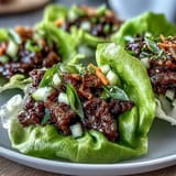 Savory marinated Korean BBQ beef piled high on cool lettuce leaves with crunchy toppings.