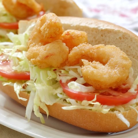 A close-up of a loaded Shrimp Po Boy, showcasing crispy shrimp on a soft French roll.