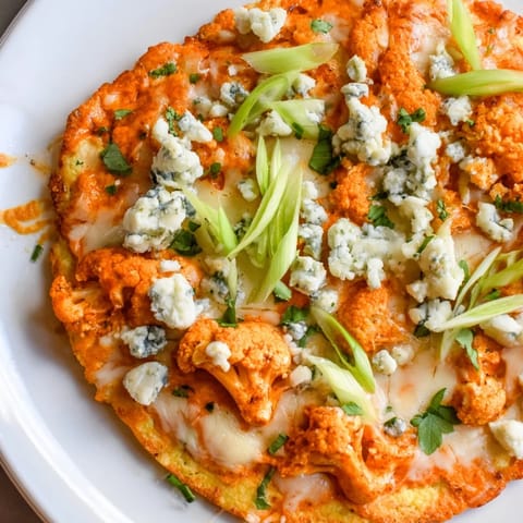 Sizzling Buffalo Cauliflower Pizza fresh from the oven, topped with crumbled blue cheese and fresh parsley on a gluten-free base.