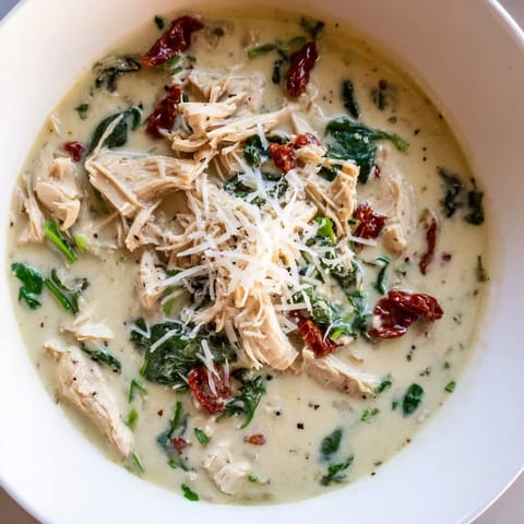 Freshly ladled Creamy Tuscan Chicken Soup in a ceramic bowl, with herb garnish and a slice of crusty bread nearby.
