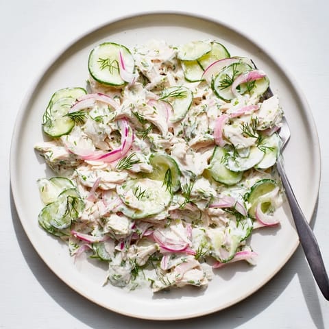 A bowl of creamy cucumber chicken salad, topped with fresh dill and green onions, served as a refreshing high-protein lunch.