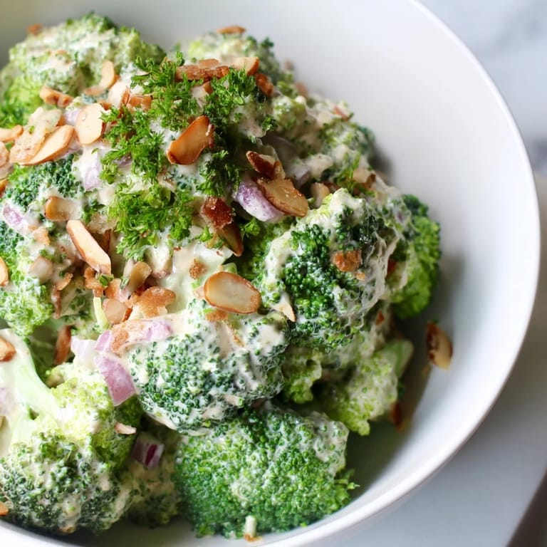 Colorful bowl of homemade Garlic Parmesan Broccoli Salad with crunchy slivered almonds, red onion, and creamy dressing, ideal as a light lunch.
